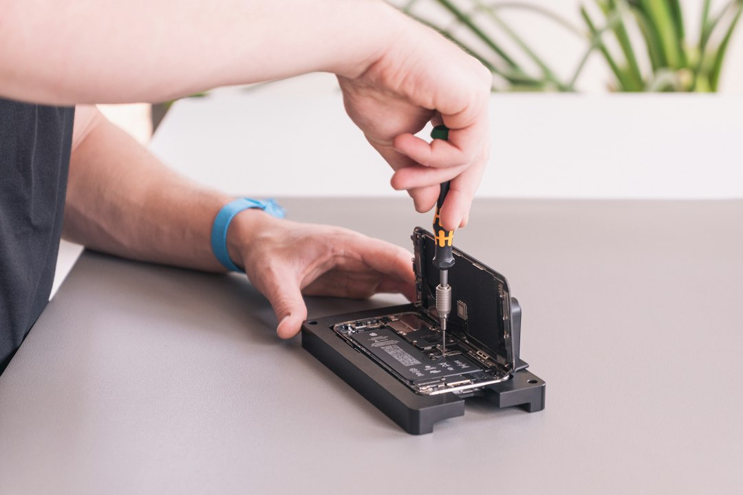 Technicien dévissant un appareil mobile sur un support de réparation